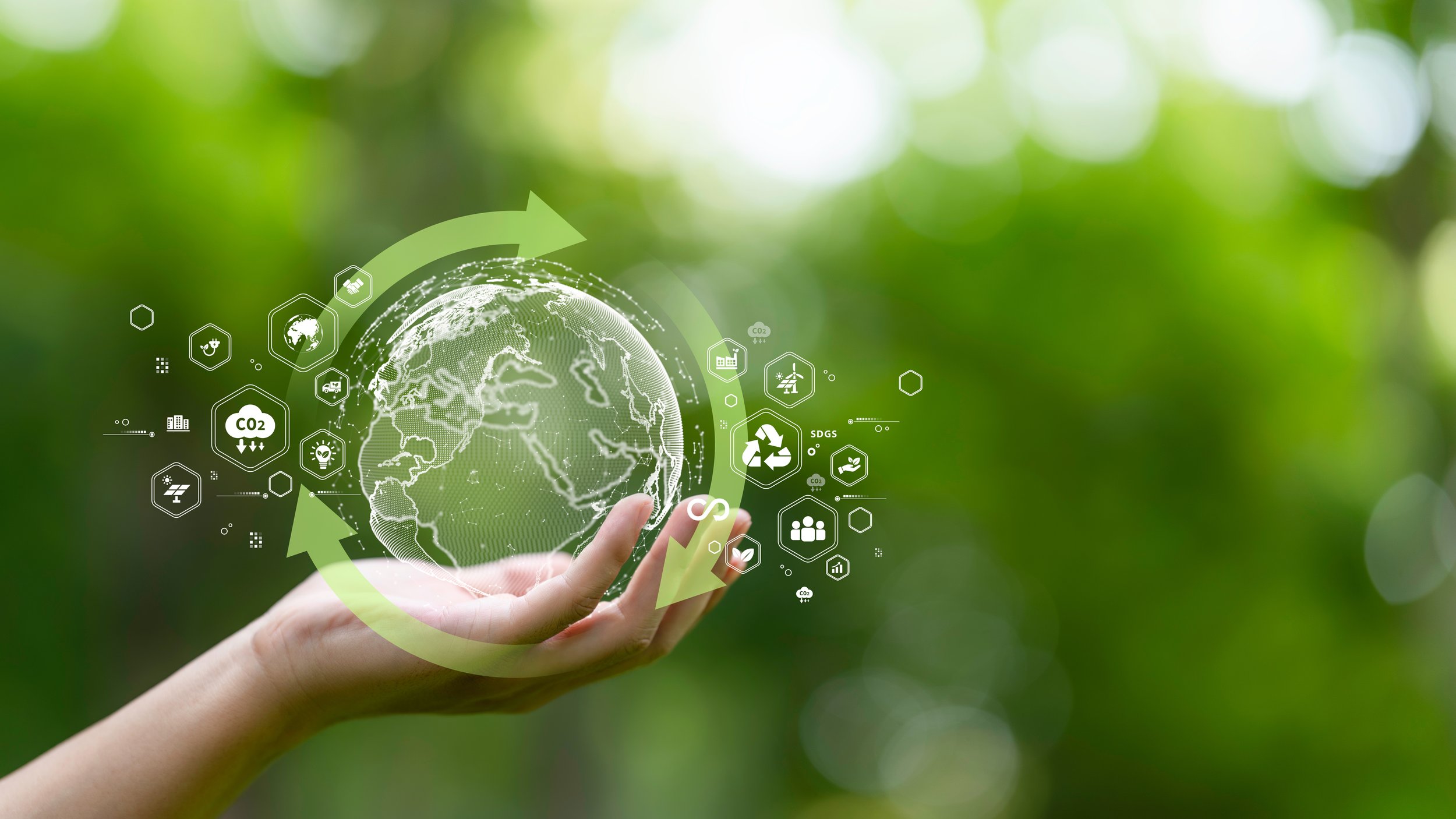 Hand holding a digital globe circled by green recycling arrows and sustainability icons