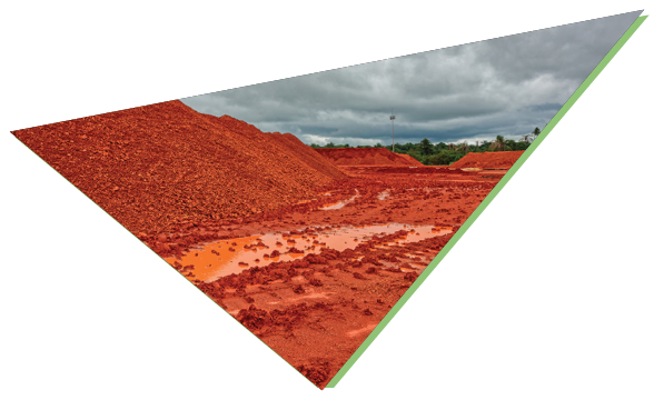 Red bauxite residue stockpiles under a cloudy sky, triangular frame