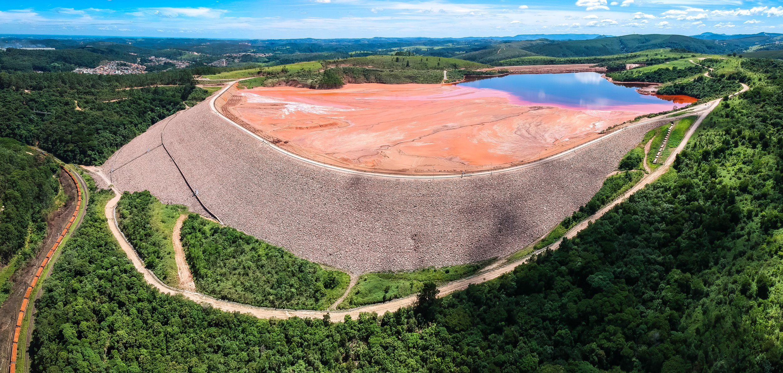 Aerial view of a red tailings pond and its containment dam